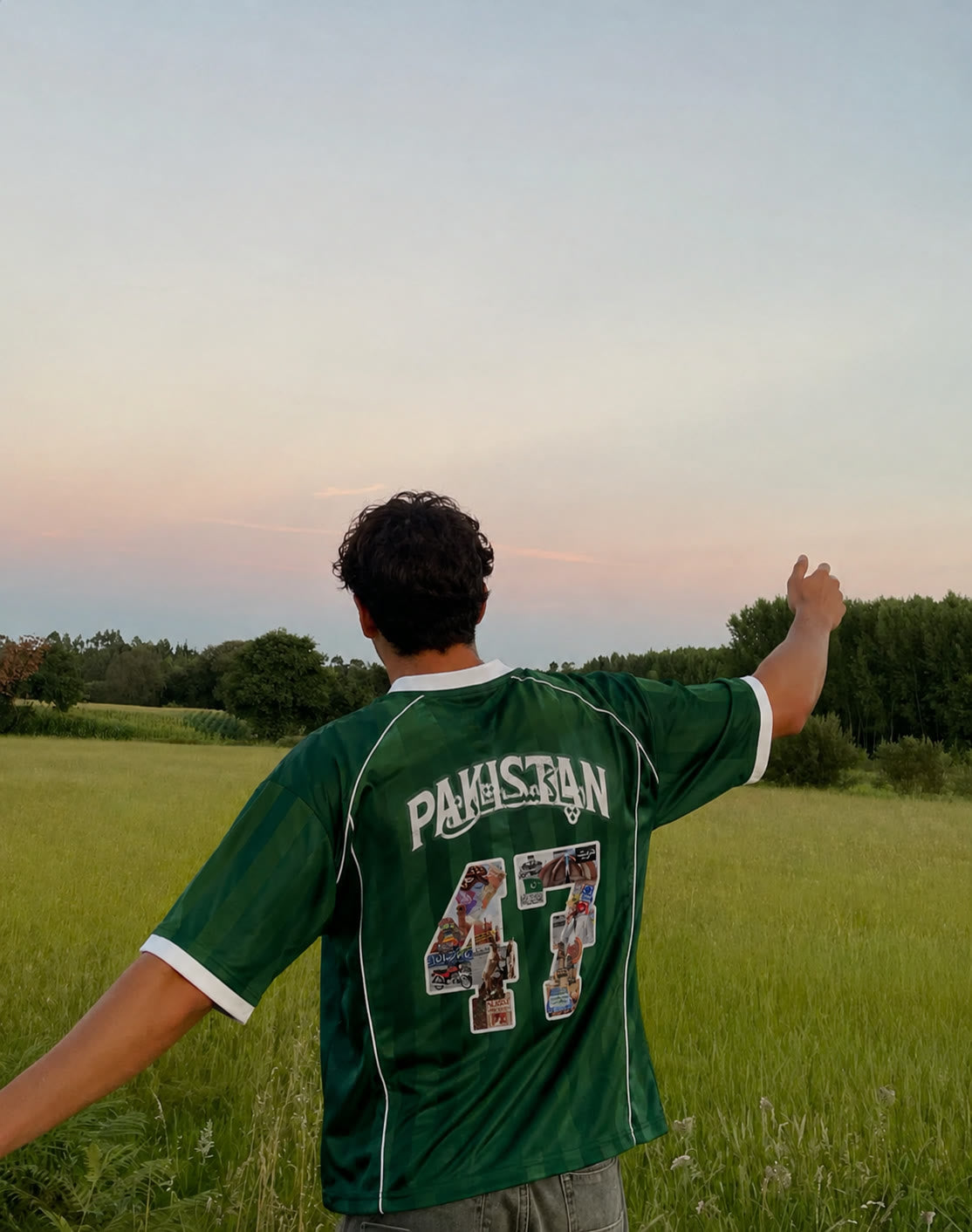 Man in a green Pakistan 47 jersey standing in a field at dusk